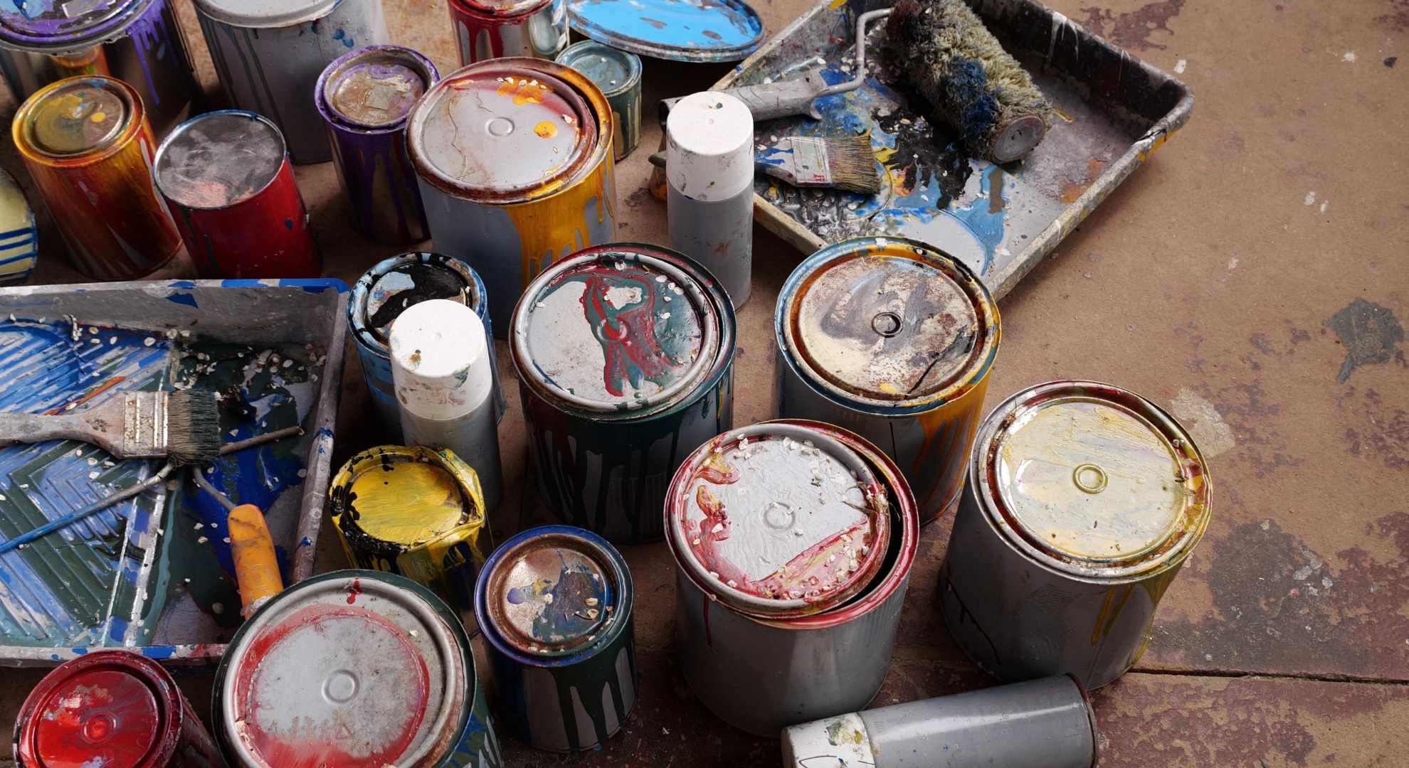 Collection of messy, used paint cans and painting tools that should not be washed down drains.